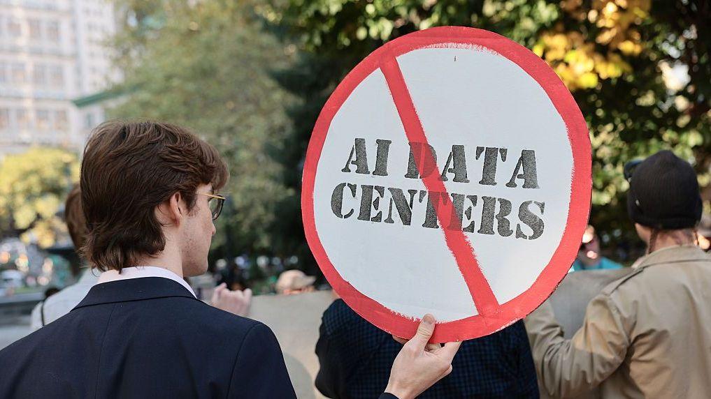 Una persona de espaldas sujeta un cartel que pide la prohibición de los centros de datos. La foto está tomada en una protesta en Nueva York. 