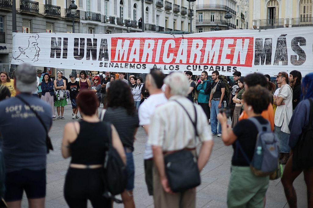 Un grupo de personas se reúne junto a una pancarta con el lema "Ni una Maricarmen más"—en referencia a una mujer de 87 años desahuciada de su vivienda en Madrid—, mientras manifestantes acampan para protestar contra los desahucios y la crisis de la vivienda frente a la sede de la Presidencia de la Comunidad de Madrid, en la Puerta del Sol.