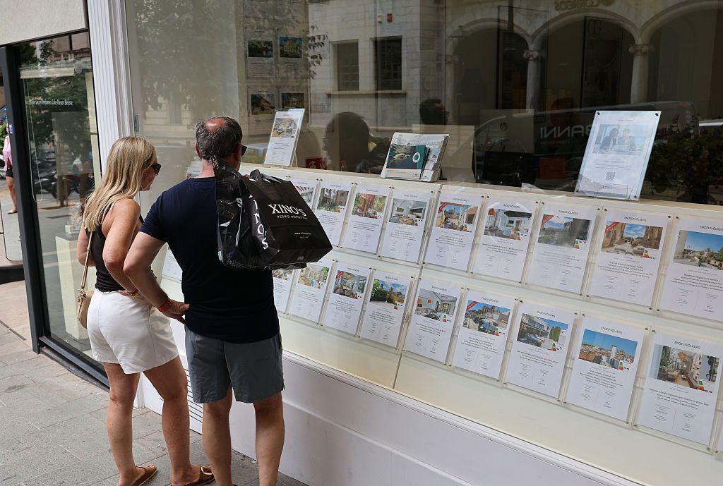 Una pareja ve los precios de unas viviendas en la vitrina de una agencia inmobiliaria en Palma de Mallorca.