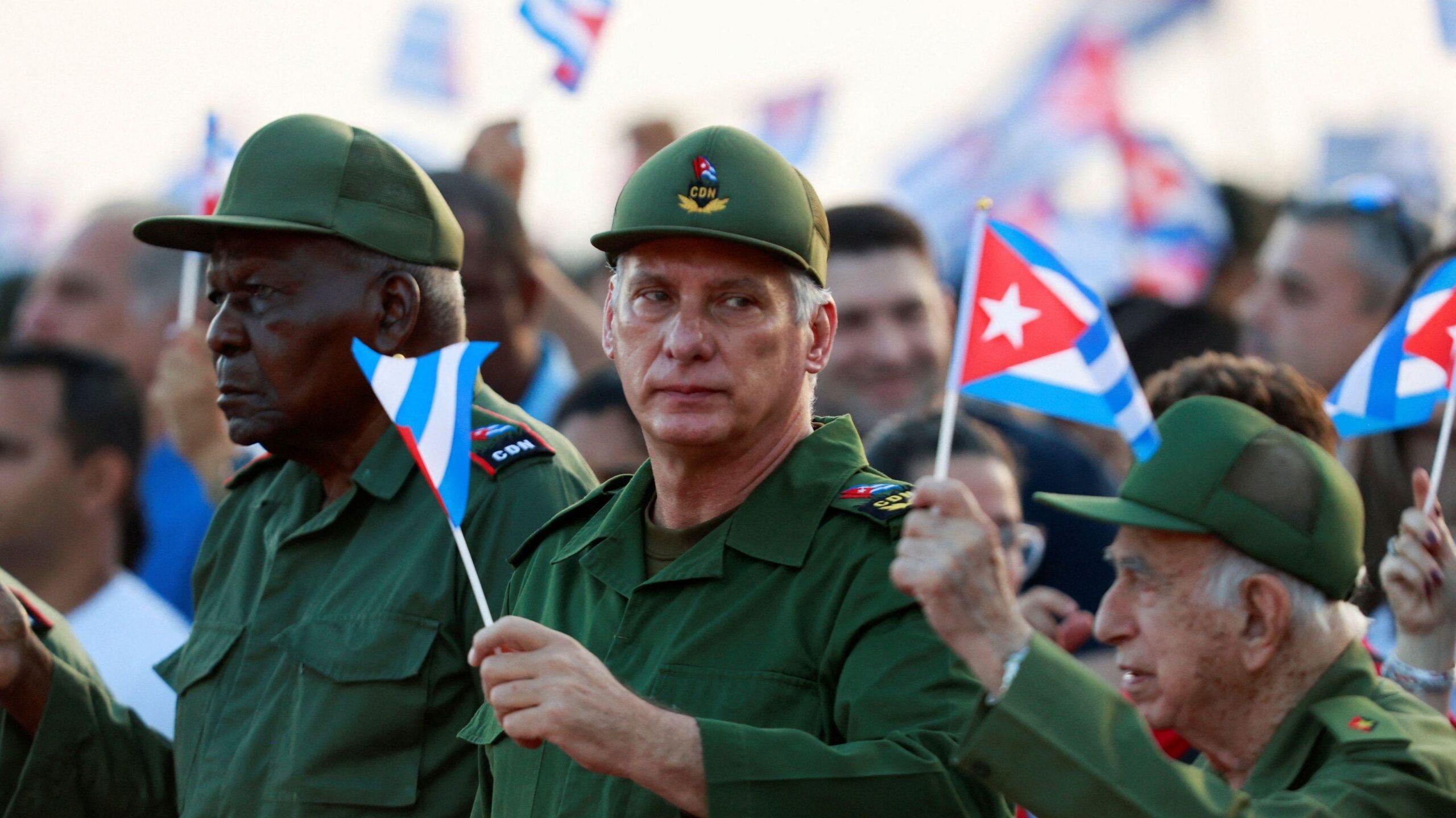 Migiel Díaz-Canel en el centro de la imagen junto a otras personas con banderas de Cuba y uniforme militar en mayo de 2026