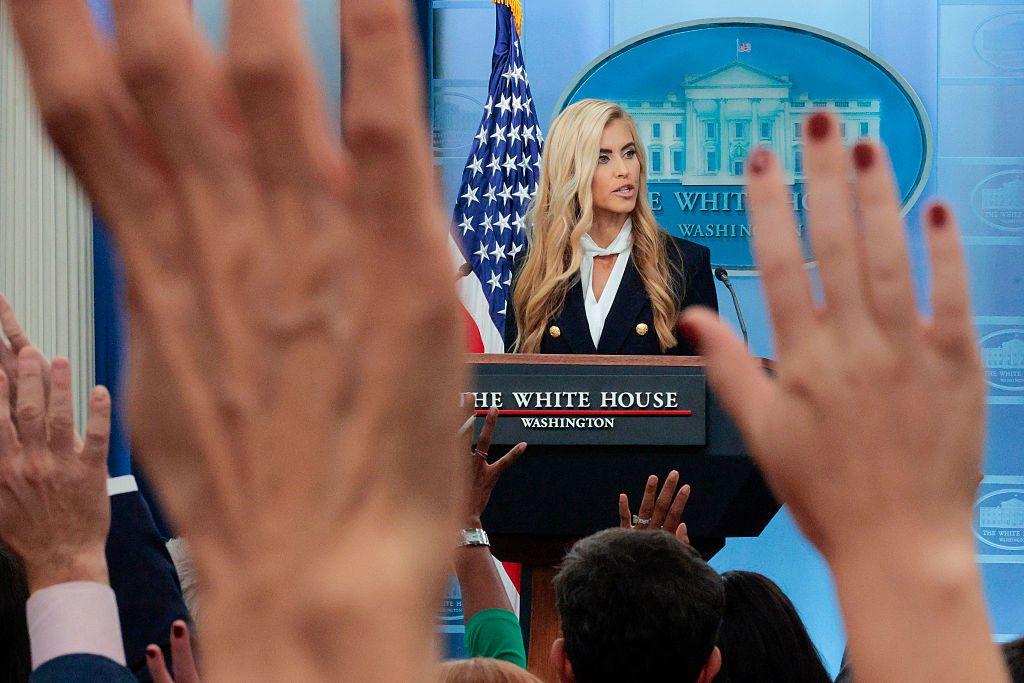 Katie Zacharia en una conferencia de prensa en la Casa Blanca. Los periodistas levantan sus manos para hacerle preguntas. 