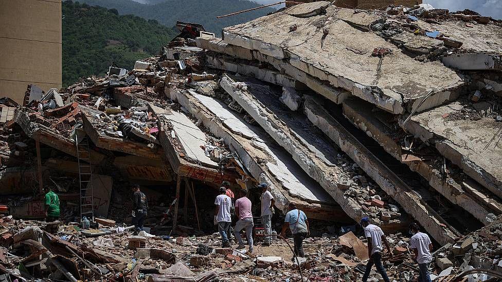 Un edificio destruido en los sismos de Venezuela en junio de 2026. Se ve a personas frente a las ruinas de una edificación en la que se ve pisos aplastados uno sobre otro