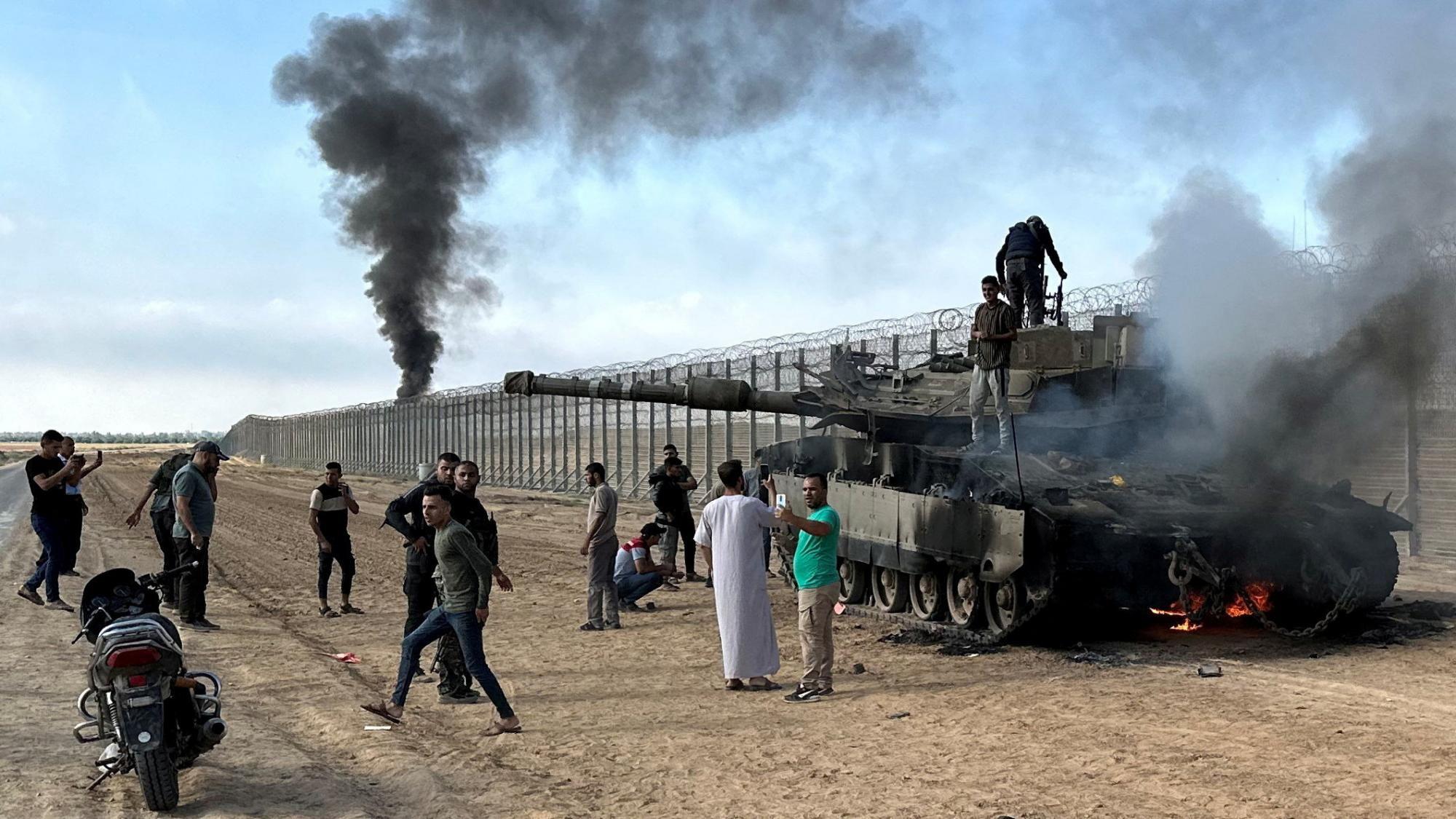 Foto de archivo que muestra a palestinos reunidos alrededor de un tanque israelí incendiado durante el ataque liderado por Hamás el 7 de octubre de 2023 contra Israel, en el lado israelí de la valla fronteriza de Gaza.