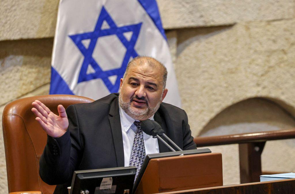 Mansour Abbas habla sentado en una silla frente a un micrófono. Detrás de él se ve una bandera de Israel.