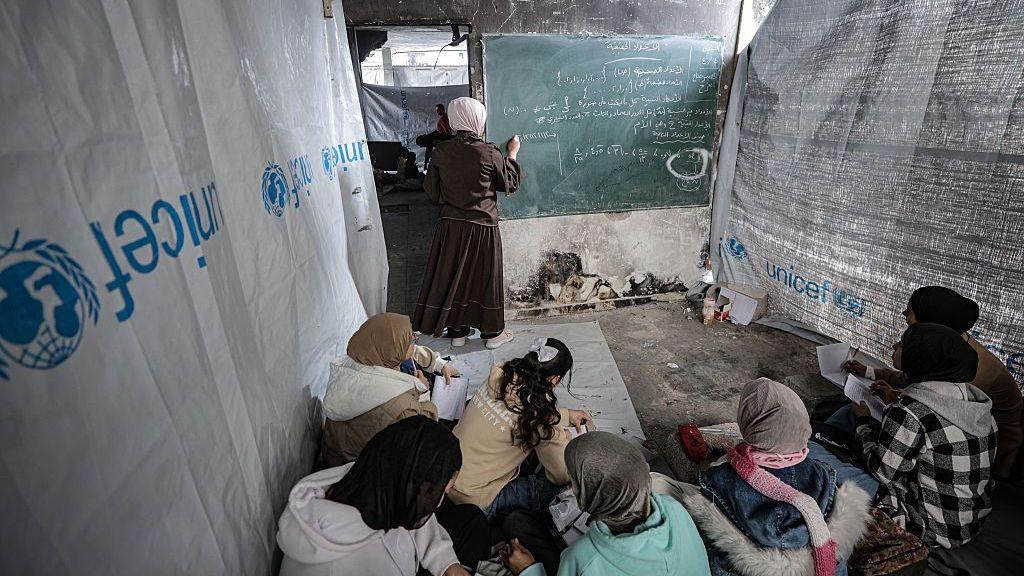 Niñas palestinas escuchan durante una clase en un aula improvisada en el campamento de refugiados de Jabalia, en el norte de Gaza (4 de abril de 2026).