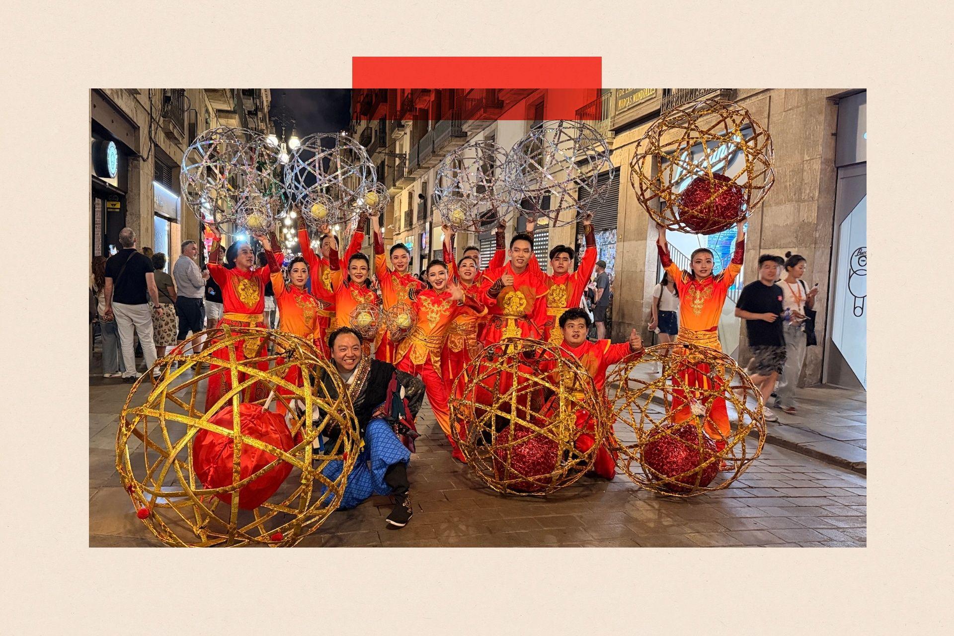 Alrededor de 15 artistas con trajes rojos posan con sus enormes adornos de plata y oro.