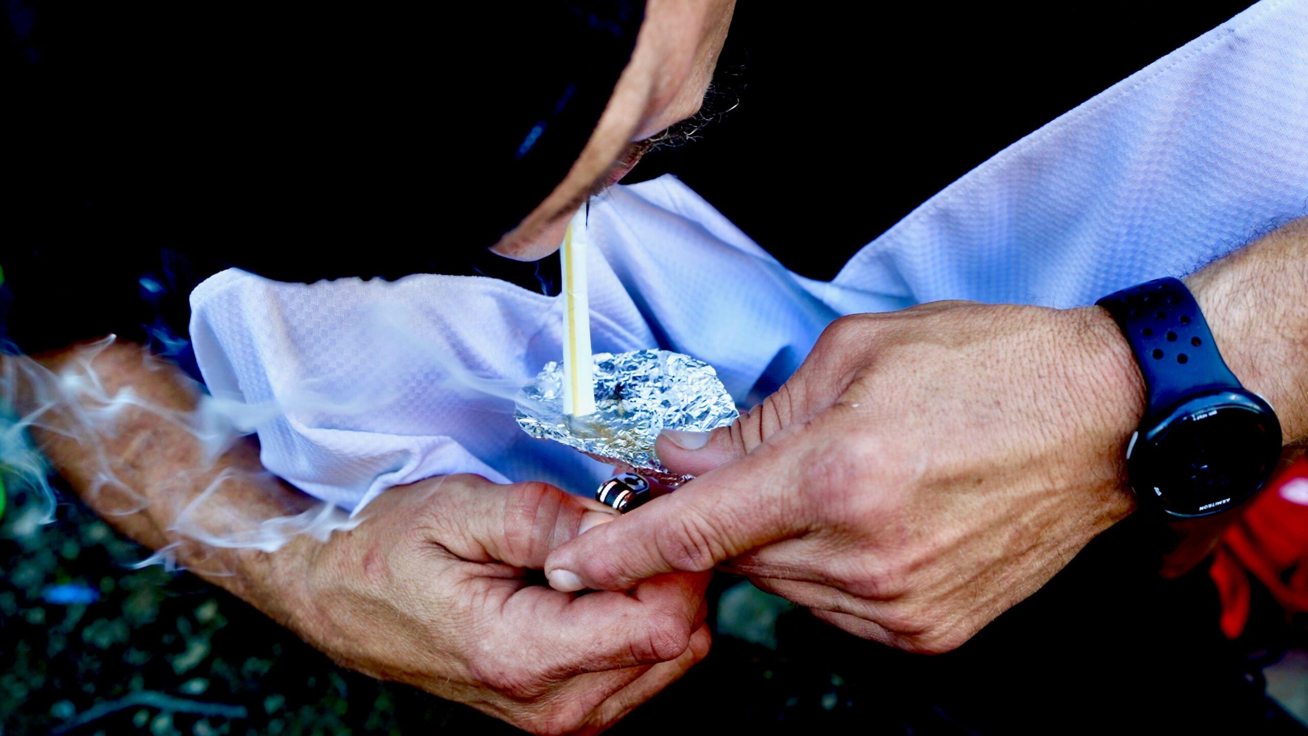 Primer plano de Mike usando un encendedor para prender fuego a unos granos de fentanilo colocados sobre papel de aluminio.