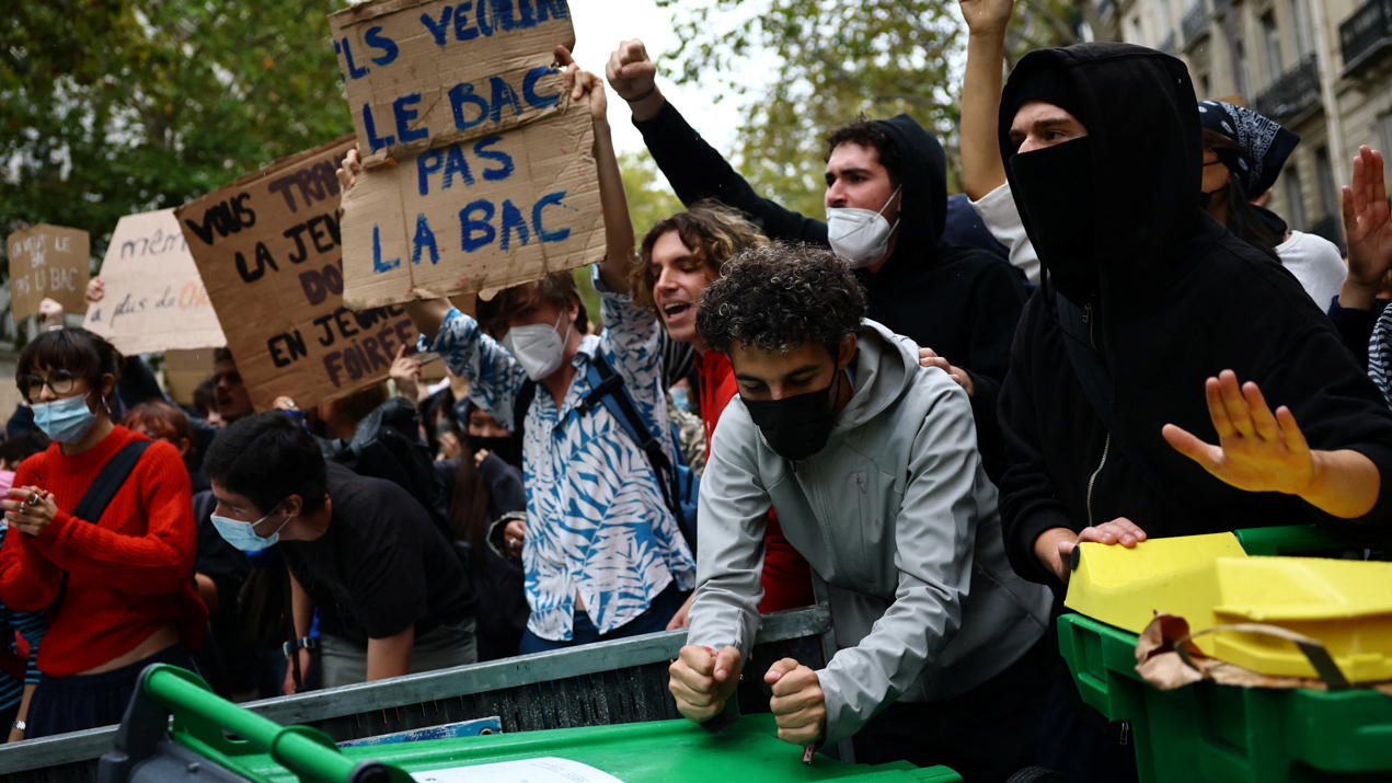Manifestantes portan pancartas detrás de una barricada para bloquear el paso en París, 7 de octubre.