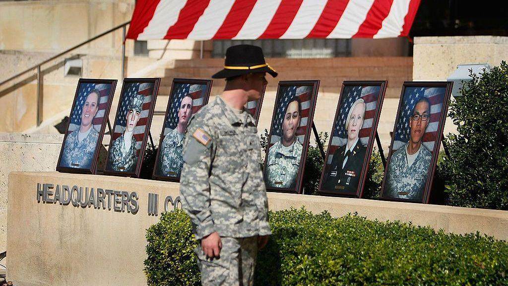 Un soldado del ejército de EE.UU. pasa junto a fotografías de militares fallecidos durante el servicio conmemorativo en honor a las 13 víctimas mortales del tiroteo de Fort Hood, Texas. 