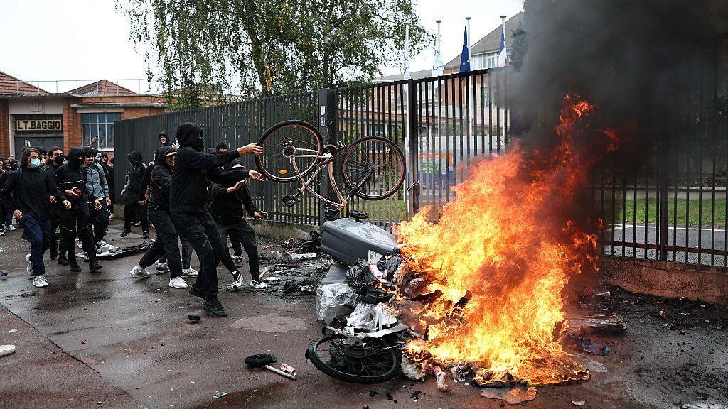 Una densa columna de humo negro se eleva desde contenedores de basura y bicicletas en llamas mientras estudiantes realizan una protesta bloqueando el acceso a la escuela secundaria Cesar Baggio durante una jornada de huelgas y manifestaciones en el sector público a nivel nacional, en Lille, el 29 de septiembre de 2026.