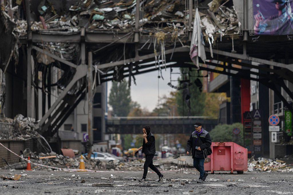 Personas caminan frente a un centro comercial dañado tras un ataque aéreo en Kyiv el 19 de octubre de 2026.