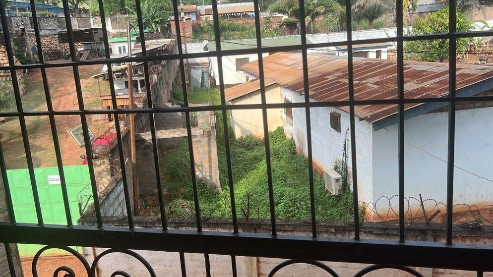 Casas con techos de lámina, una calle de tierra y un muro con alambre razor vistos desde el alojamiento de los migrantes deportados en Bangui, República Centroafricana.