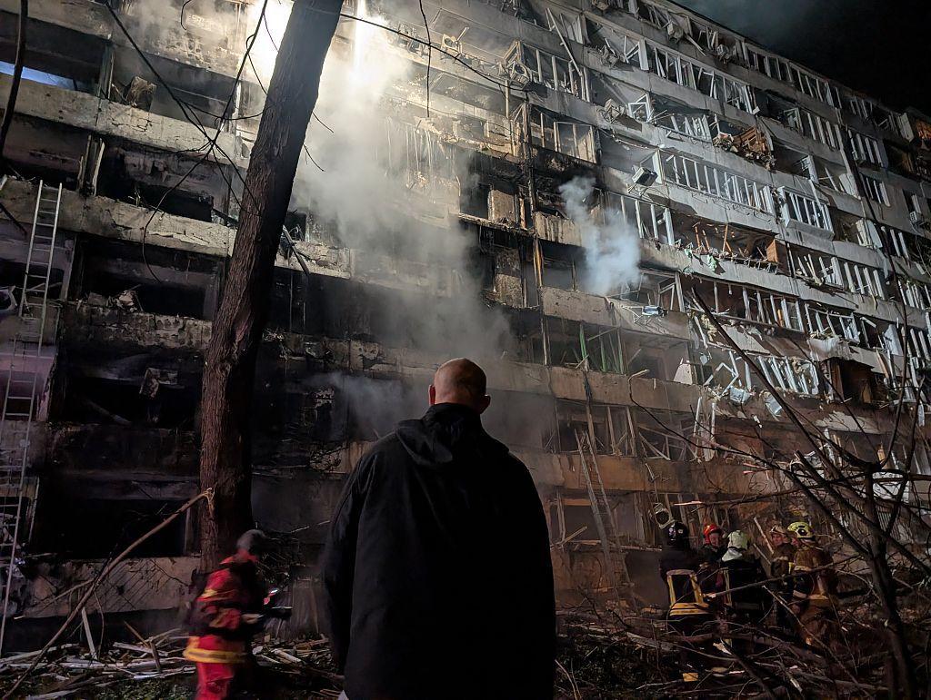 Un hombre está parado frente a un edificio de apartamentos dañado y humeante mientras los bomberos trabajan tras un bombardeo ruso el 14 de octubre de 2026 en Kyiv, Ucrania. Las fuerzas rusas continúan lanzando ataques masivos contra las zonas residenciales e infraestructuras de Kiev utilizando misiles balísticos y drones "Shahed"