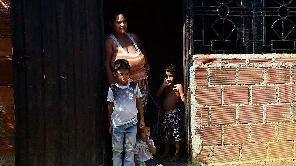oLa panadera informal y exauxiliar de enfermería Luisana Serrano, de 34 años, junto a sus hijos en la entrada de su casa en el asentamiento La Fortaleza, cerca de Cúcuta, Colombia, el 9 de enero de 2026.