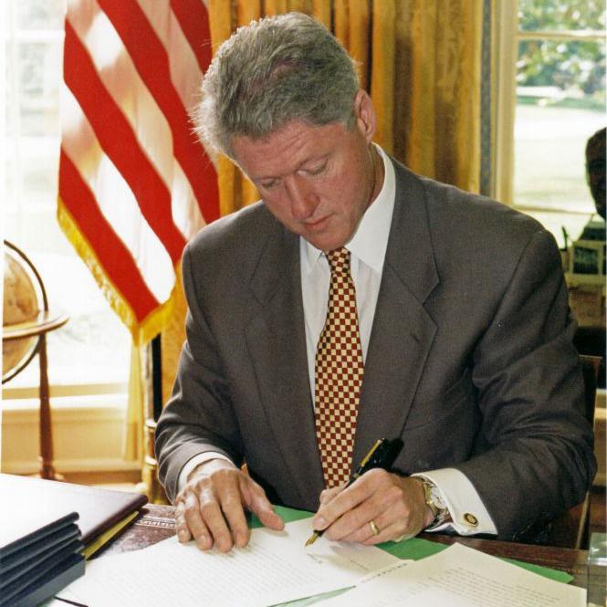 Bill Clinton firma un papel