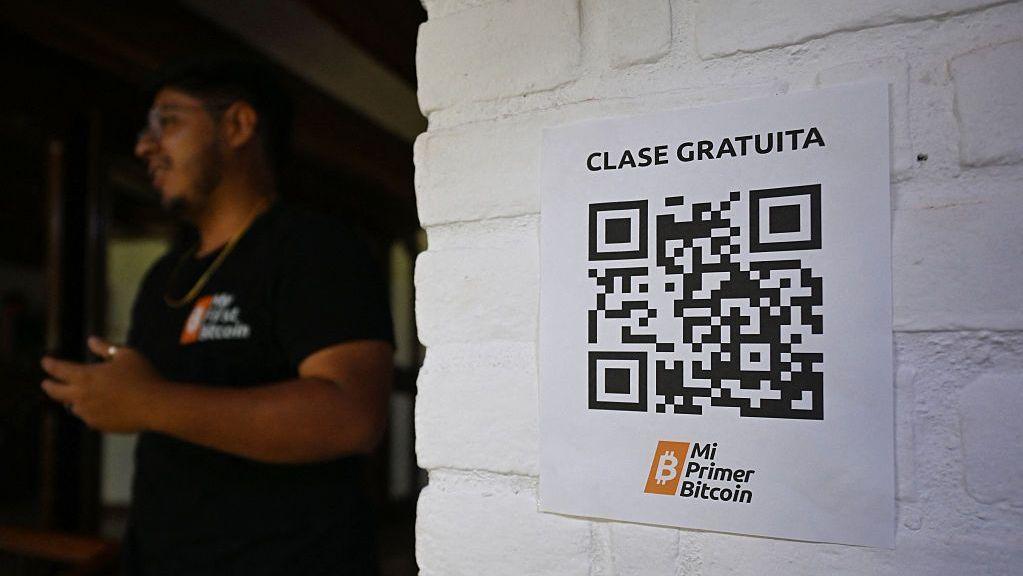 Un cartel con un código QR invita a clases gratuitas de educación sobre criptomonedas en la sede de la ONG Mi Primer Bitcoin en San Salvador, el 16 de julio de 2025. (Foto de Marvin RECINOS / AFP) (Foto de MARVIN RECINOS/AFP vía Getty Images)