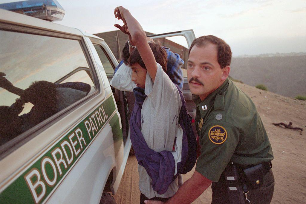 Un miembro de la Patrulla Fronteriza revisa a un detenido en 1994.