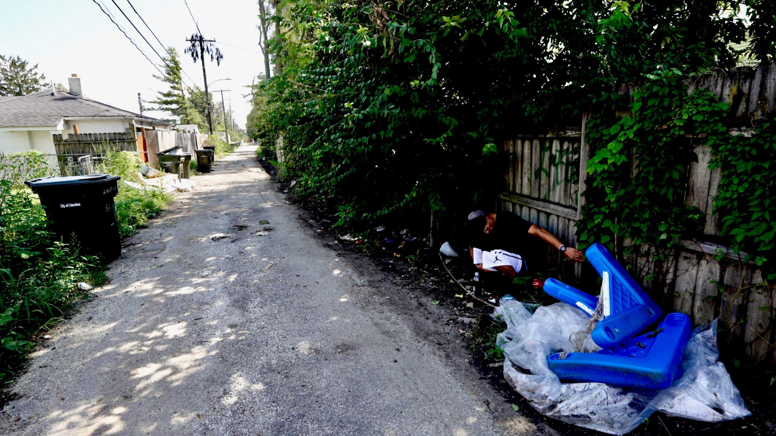 Un callejón con Mike agachado en el suelo a la derecha. 