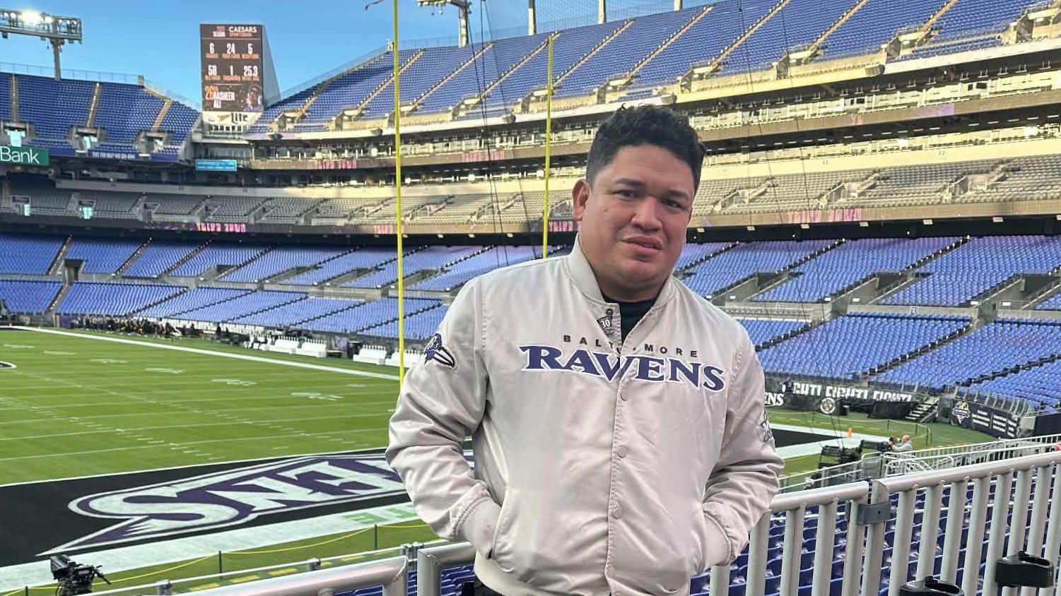 Luis Mendoza posa con la chaqueta de los Ravens en el M&T Bank Stadium en Baltimore, Maryland, Estados Unidos.